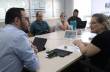 #DescricaodaImagem; foto da reunião onde estão Secretário Mateus Wesp de camisa azul clara, e a Vice presidente do Coepede Liza Cenci os dois apoiados sobre uma mesa bege, algumas folhas, celulares e copos de água sobre a mesa, ao fundo mais três pessoas 